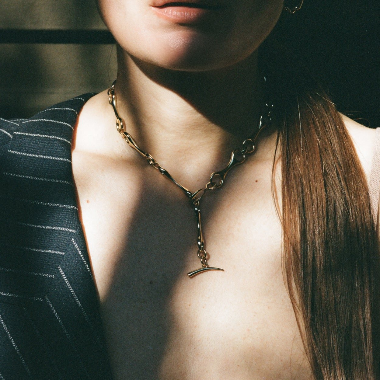 A woman with long hair adorned in a 40mm Grande Double Beam gold vermeil chain necklace- Gabriela Artigas